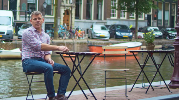 Man sitting at table beside canal in Amsterdam